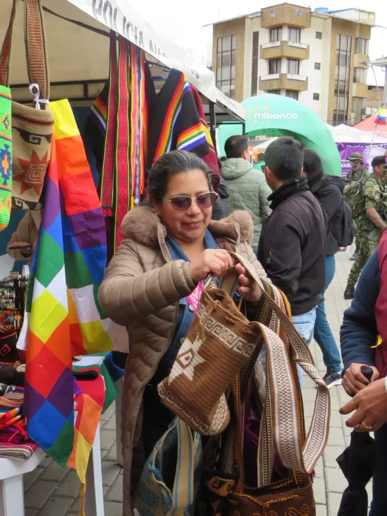 Tejedora del grupo mostrando los tejidos a una clienta en la feria